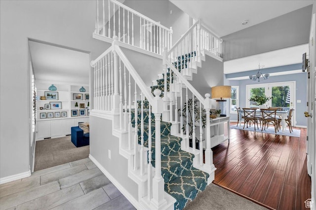 stairs with a chandelier, baseboards, and a high ceiling