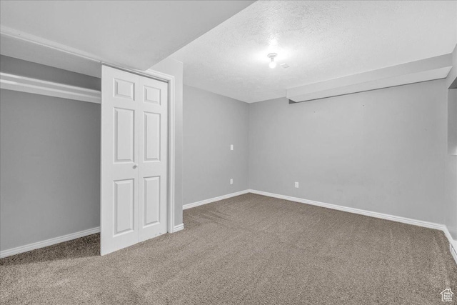 finished below grade area with carpet flooring, a textured ceiling, and baseboards