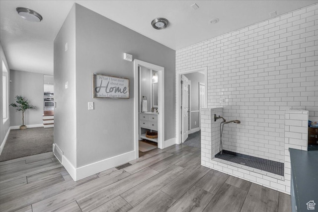 full bathroom featuring tiled shower, wood finished floors, and baseboards