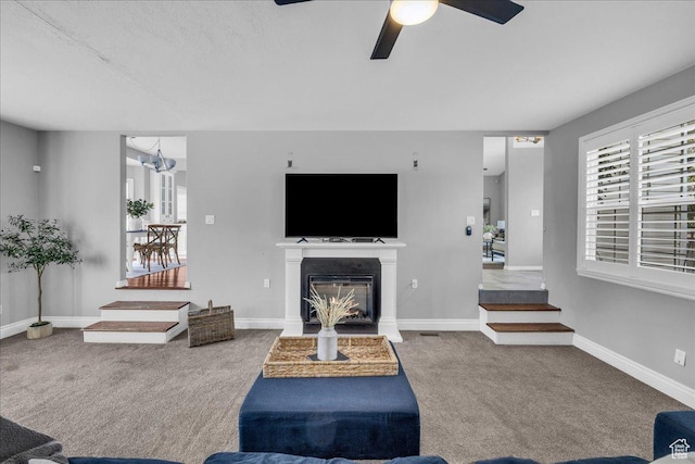 living area featuring carpet floors, healthy amount of natural light, ceiling fan, and a glass covered fireplace