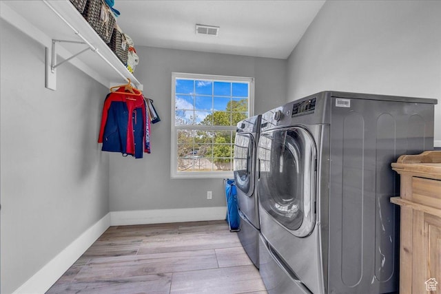 laundry room with washer and clothes dryer, wood finished floors, and baseboards