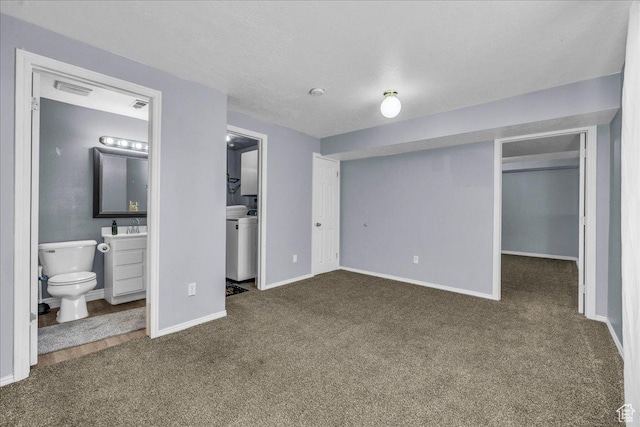 unfurnished bedroom with carpet, a walk in closet, baseboards, ensuite bath, and a sink