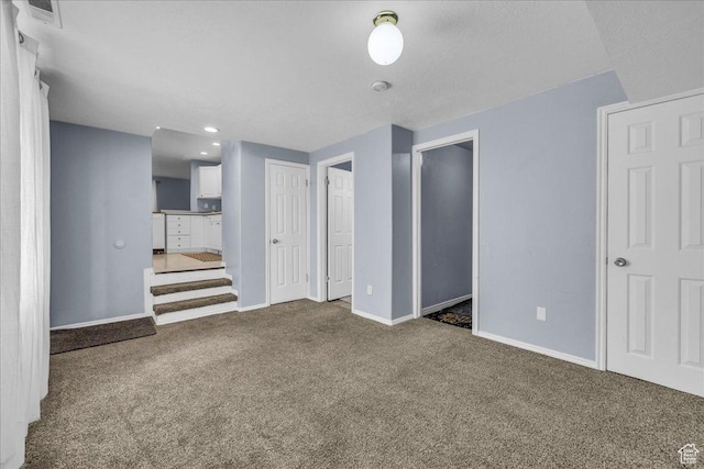 unfurnished living room featuring carpet floors, baseboards, and stairs
