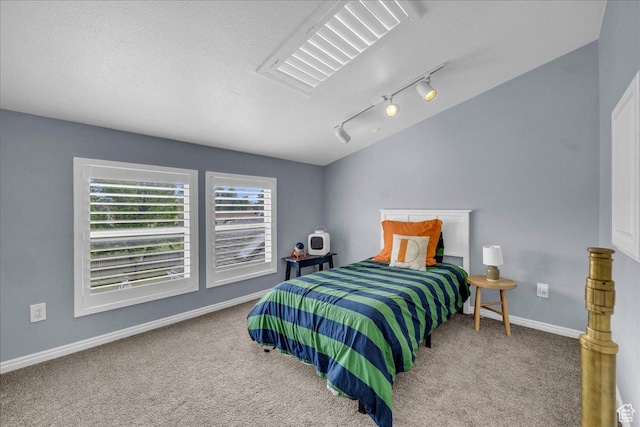 bedroom featuring carpet floors, rail lighting, baseboards, and a textured ceiling