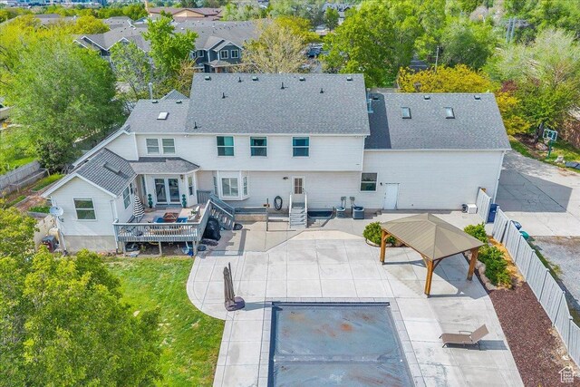 back of house with a deck, a patio area, and a shingled roof