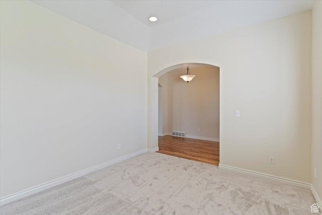 carpeted spare room with arched walkways and baseboards