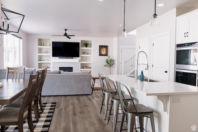 14944 S Beckham Dr W, Herriman, UT 84096 - dining room with a ceiling fan, wood finished floors, a fireplace, recessed lighting, and built in shelves