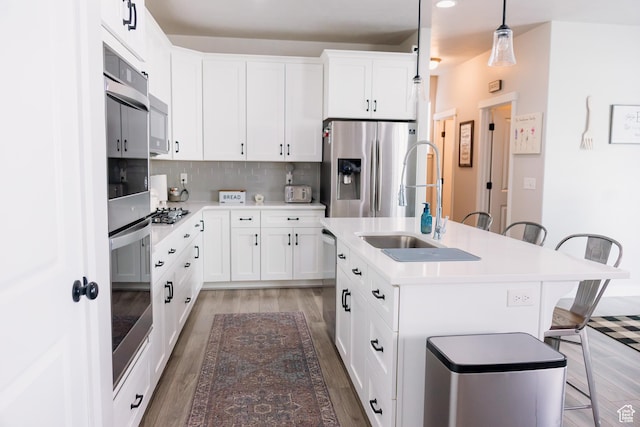 14944 S Beckham Dr W, Herriman, UT 84096 - kitchen featuring appliances with stainless steel finishes, a breakfast bar area, light wood finished floors, a sink, and tasteful backsplash