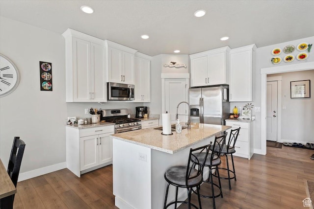 kitchen with stainless steel appliances, a sink, dark wood-type flooring, a breakfast bar, and white cabinets