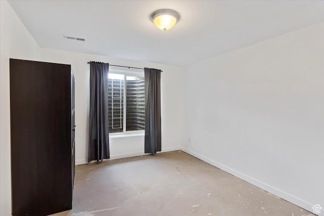unfurnished room featuring baseboards and concrete flooring