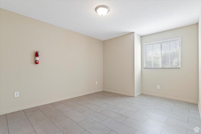 unfurnished room with baseboards and light tile patterned floors