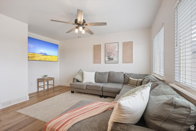 living area with wood finished floors, a ceiling fan, healthy amount of natural light, and baseboards
