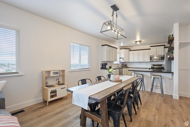 dining area with plenty of natural light, light wood-type flooring, and baseboards