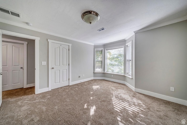 unfurnished bedroom with carpet flooring, baseboards, ornamental molding, and a textured ceiling