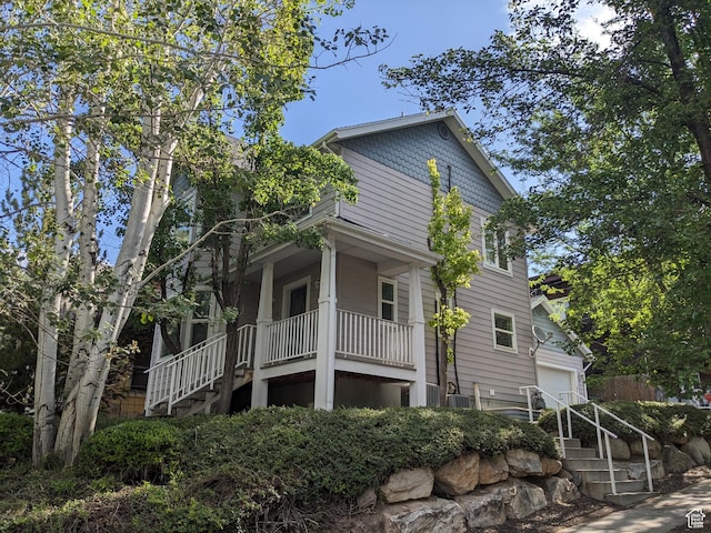 view of property exterior featuring stairway, a garage, and covered porch