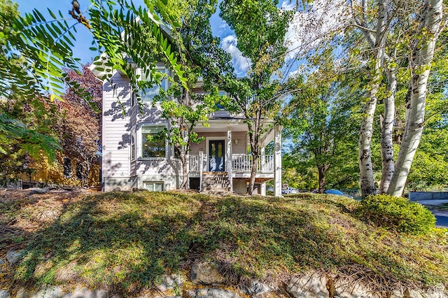 view of property hidden behind natural elements with covered porch