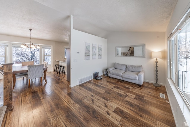 1501 W 2060 S, Woods Cross, UT 84087 - living area with a textured ceiling, dark wood-style flooring, a chandelier, baseboards, and lofted ceiling