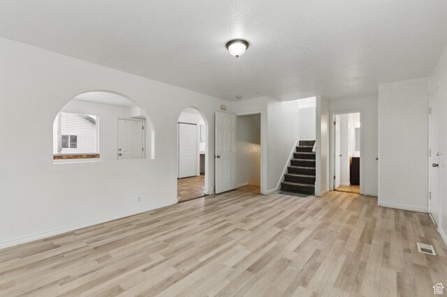 677 E 700 N, Tooele, UT 84074 - unfurnished living room featuring stairs, light wood finished floors, baseboards, and arched walkways