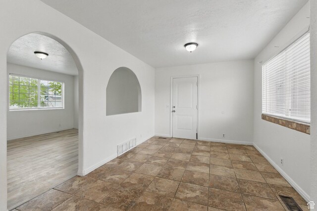 677 E 700 N, Tooele, UT 84074 - empty room featuring baseboards, a textured ceiling, arched walkways, and stone finish floors