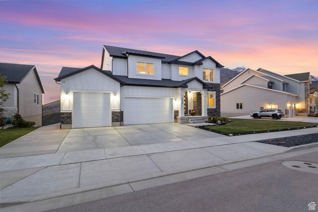 view of front of house featuring board and batten siding, stone siding, concrete driveway, a garage, and an attached garage