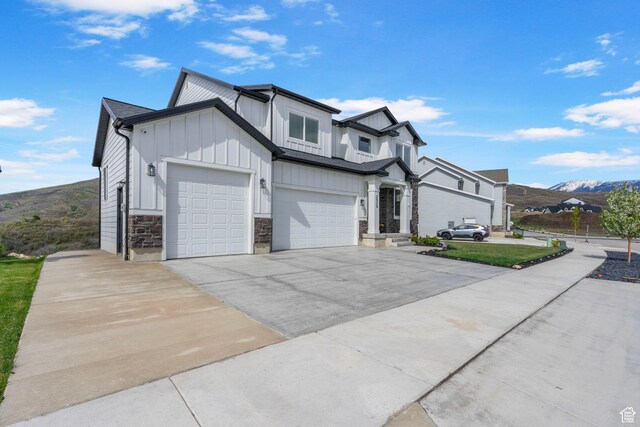 modern farmhouse style home with board and batten siding, concrete driveway, stone siding, a garage, and an attached garage