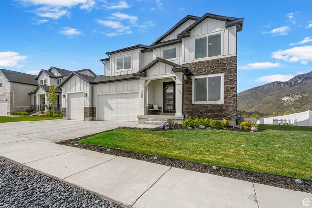 view of front of home with board and batten siding, stone siding, concrete driveway, and a mountain view