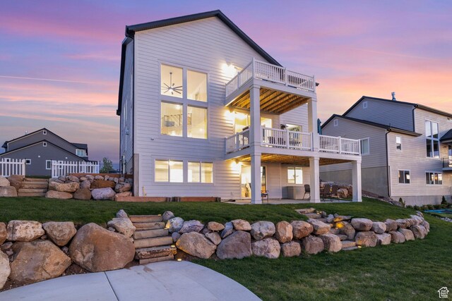 rear view of house with a balcony, a patio area, and a yard