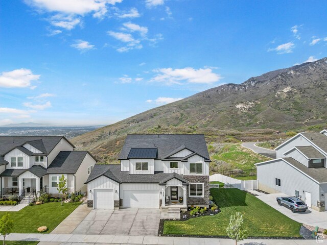 view of front facade featuring board and batten siding, stone siding, driveway, a mountain view, and a residential view