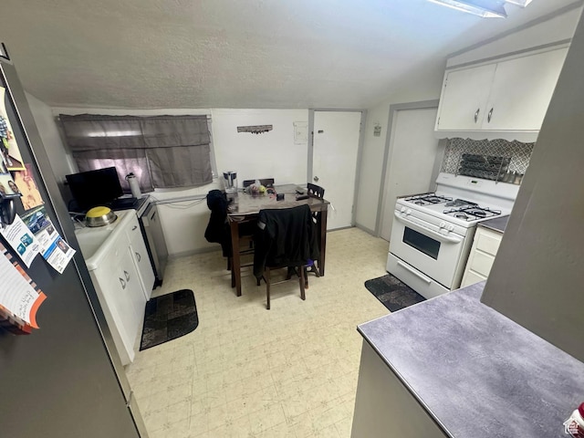 kitchen with gas range gas stove, light floors, white cabinetry, an office area, and decorative backsplash