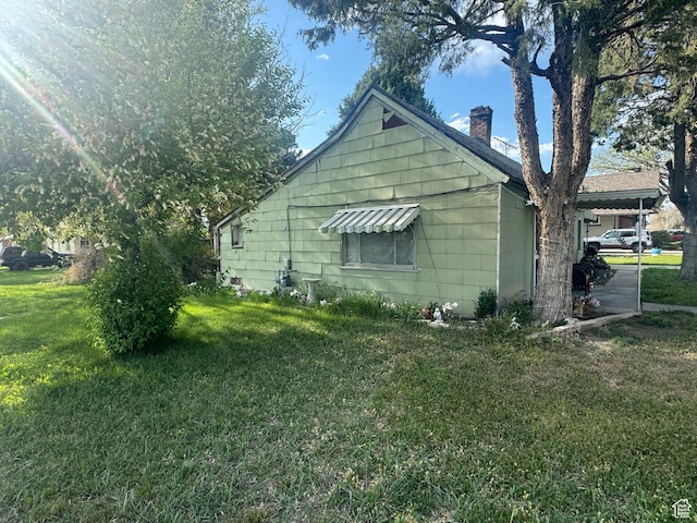 view of side of property featuring a chimney and a lawn