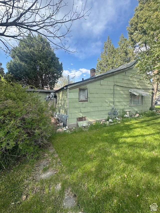 view of side of property with a yard and a chimney