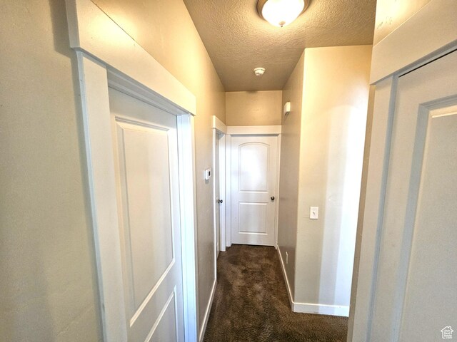 1771 E Skyline Dr Unit I4, Eagle Mountain, UT 84005 - hall with a textured ceiling, baseboards, and dark carpet
