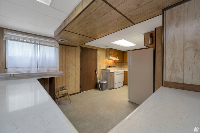825 W Arapahoe Ave S, Salt Lake City, UT 84104 - kitchen with white appliances, under cabinet range hood, wood walls, light flooring, and brown cabinetry