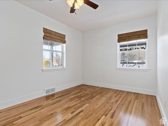 spare room featuring ceiling fan, light wood finished floors, and baseboards