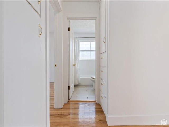 hall with light wood-style flooring and baseboards