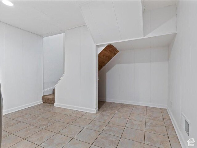 additional living space featuring a decorative wall, light tile patterned floors, and stairs