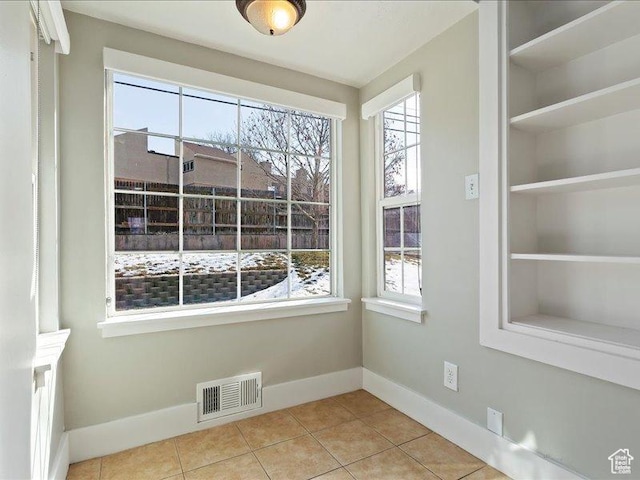 unfurnished dining area with baseboards, healthy amount of natural light, and tile patterned flooring