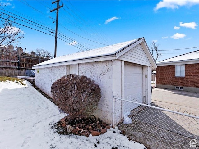 snow covered garage with fence and a garage