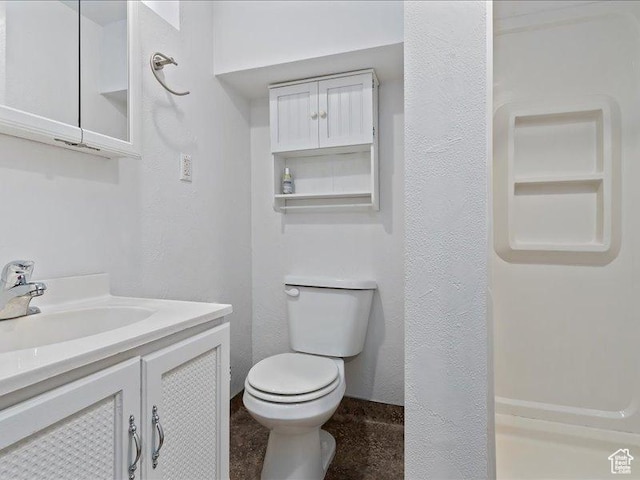 bathroom with toilet, vanity, and a textured wall
