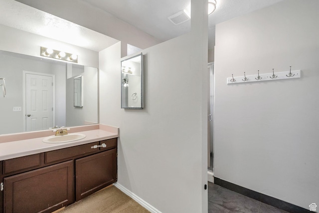 bathroom featuring baseboards, vanity, and a shower with door