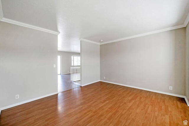 unfurnished living room featuring wood finished floors, crown molding, and baseboards
