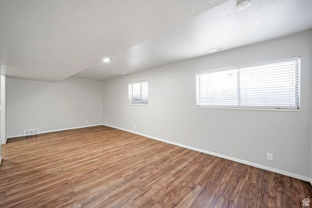 empty room with baseboards, a smoke detector, wood finished floors, and a textured ceiling