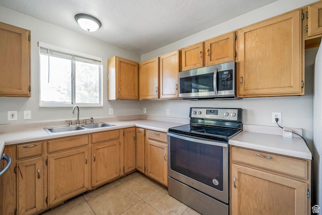 kitchen with appliances with stainless steel finishes, a sink, light countertops, and light tile patterned floors