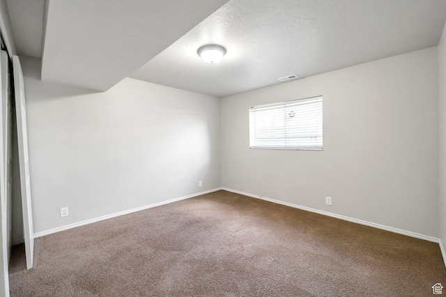 spare room featuring dark colored carpet and baseboards