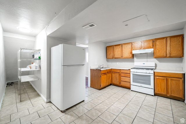 kitchen featuring white appliances, under cabinet range hood, light countertops, and a sink