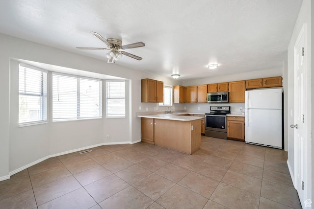 kitchen featuring appliances with stainless steel finishes, light countertops, light tile patterned floors, and a peninsula