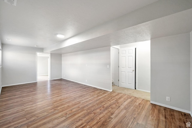 finished below grade area featuring wood finished floors and baseboards