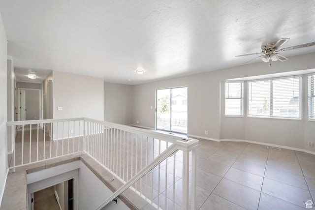 empty room with baseboards, a ceiling fan, and light tile patterned floors