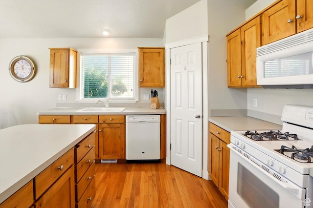kitchen featuring white appliances, a sink, light wood-style flooring, light countertops, and brown cabinetry