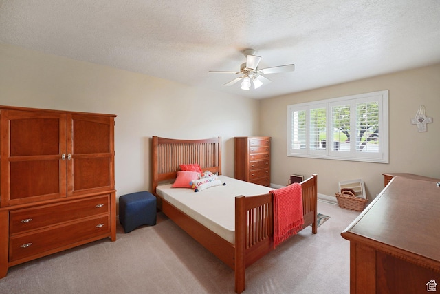 bedroom with light carpet, a ceiling fan, and a textured ceiling